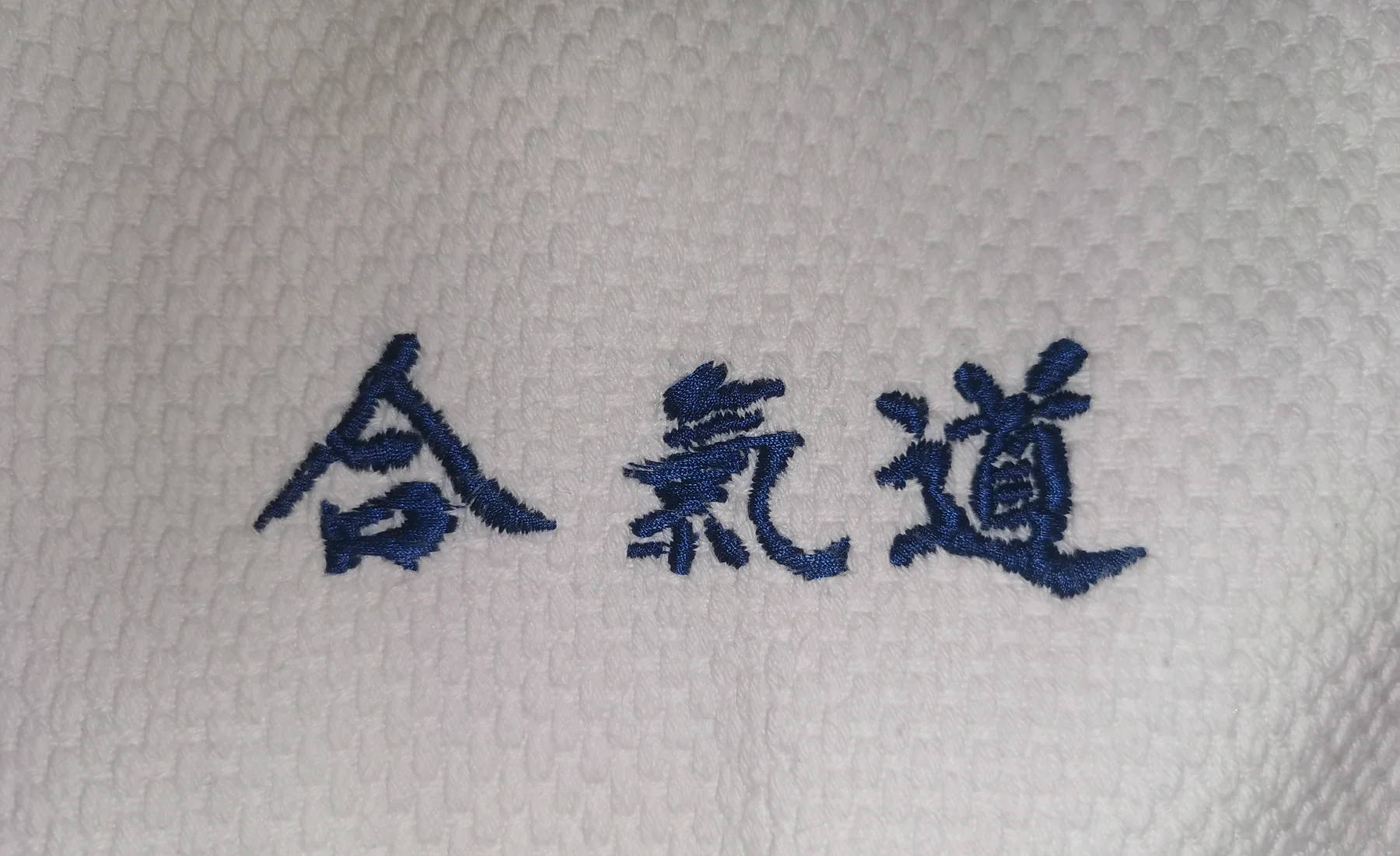 Broderie machine bleue réalisée sur un aïkidogi